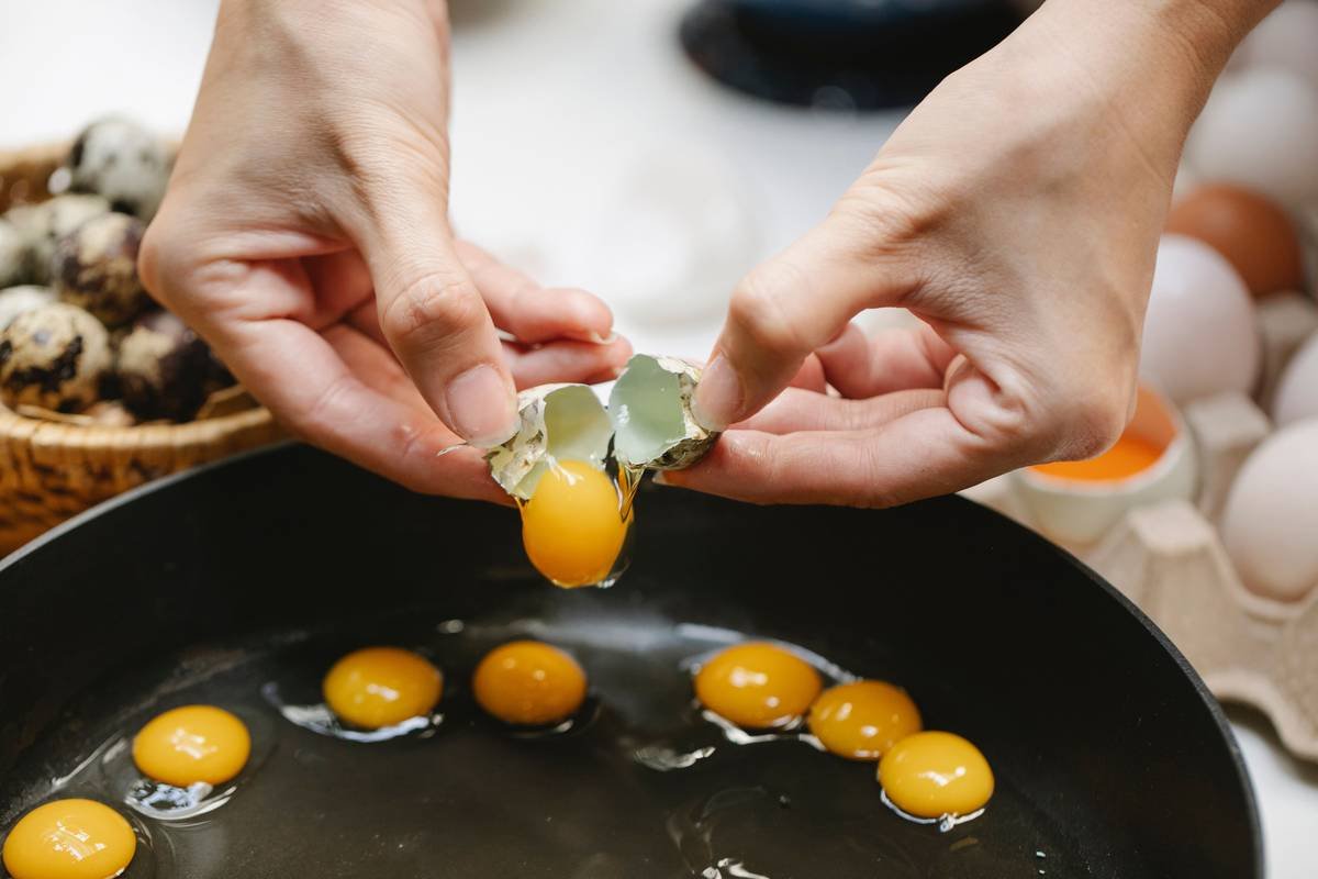 Close-up of perfectly shaped poached eggs steaming in a metal egg poacher pan, illustrating poaching eggs in egg poacher technique