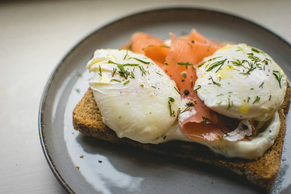 A chef arranging poached eggs on rustic toast with herbs, showcasing different techniques in presenting egg dishes